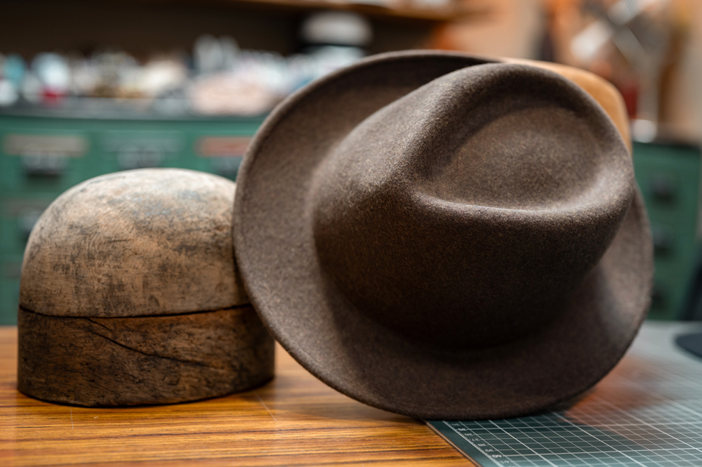 Sombrero trilby de fieltro color madera sobre fondo neutro
